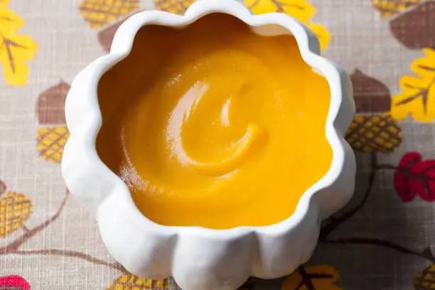 Photo of Pumpkin and carrot cream soup in bowl. Top view. Close up.