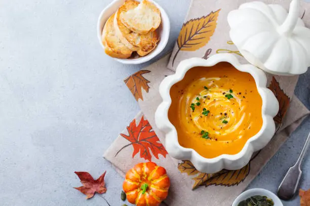 Photo of Pumpkin soup in bowl on grey stone background. Copy space. Top view.