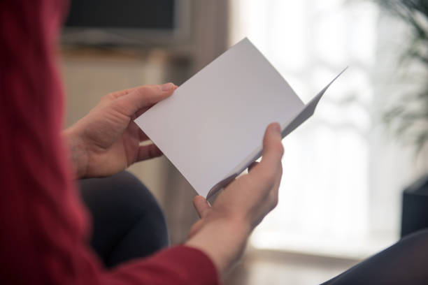 istock Woman looking at small blank white brochure with copy space 1177030642