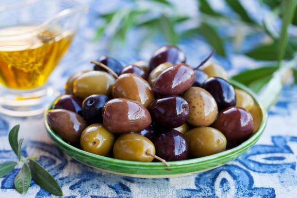 istock Assortment of fresh olives on a plate with olive tree brunches. Blue background. 1177030900