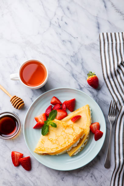 istock Crepes, thin pancakes with cream cheese, fresh strawberries. Marble background. Top view. Copy space 1177030956