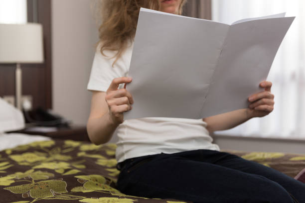 joven rubia mirando en un folleto en blanco con espacio de copia - newspaper reading blank women fotografías e imágenes de stock