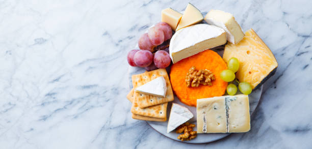 assortimento di formaggi, uva e cracker. sfondo marmoreo. vista dall'alto. copiare lo spazio. - fruit and cheese foto e immagini stock