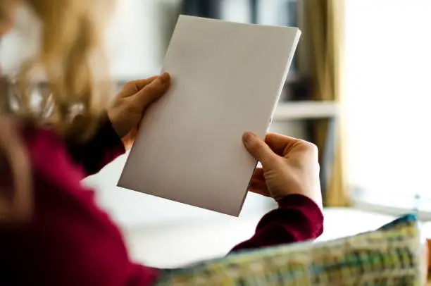 Photo of Woman holding white blank brochure with copy space