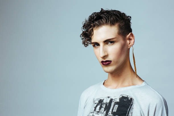 Portrait of a beautiful young man with lipstick and earring Portrait of a beautiful young man with lipstick and earring man gay stock pictures, royalty-free photos & images