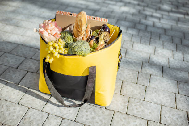 Thermal bag full of fresh food, flowers and pizza boxes to delivery on the pavement outdoors. Fresh products delivery concept