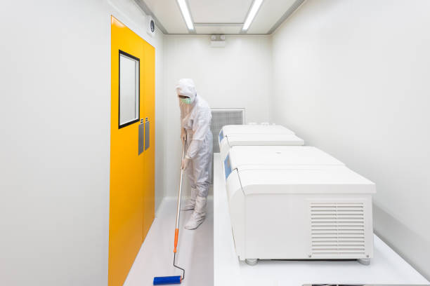 A scientist in sterile coverall gown using lint roller for cleaning laboratory. Cleanroom facility. stock photo
