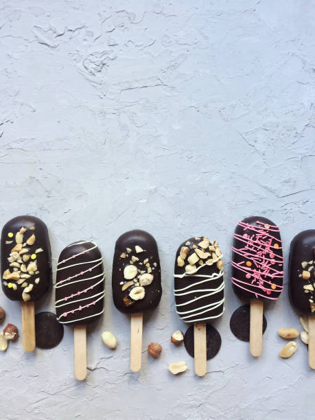 istock Chocolate popsicle cakes on a stick with nuts on a gray background. 1177041934