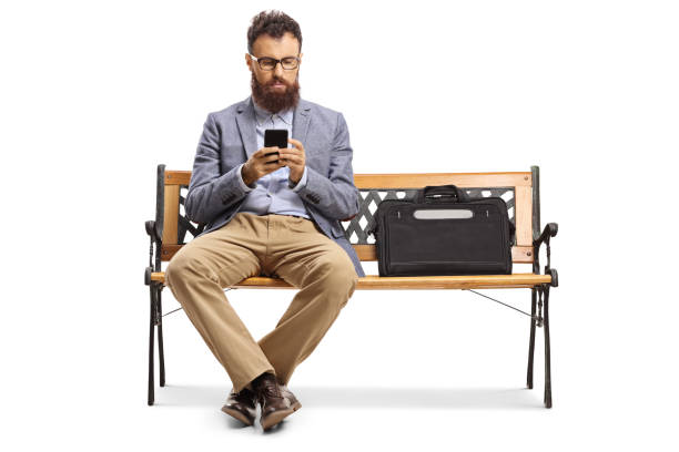 istock Bearded man typing on a mobile phone and sitting on a bench 1177047665
