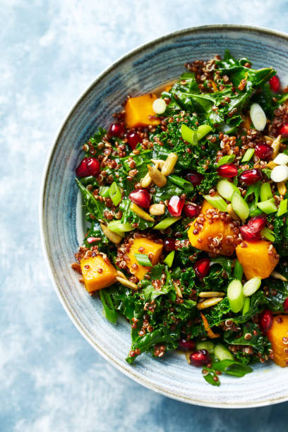 Hokkaido pumpkin and quinoa salad with kale, pomegranate, spring onion and toasted sunflower seeds. Healthy homemade food. Vegan food stock photo