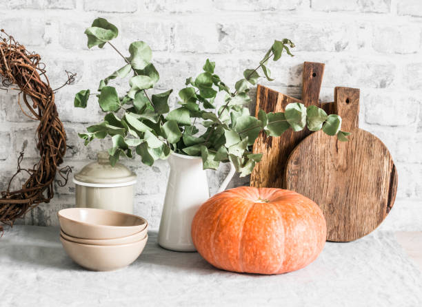 Kitchen autumn still life. Crockery, cutting boards, vine wreath, pumpkin on the table, on a light background. Rustic cozy style. Flat lay