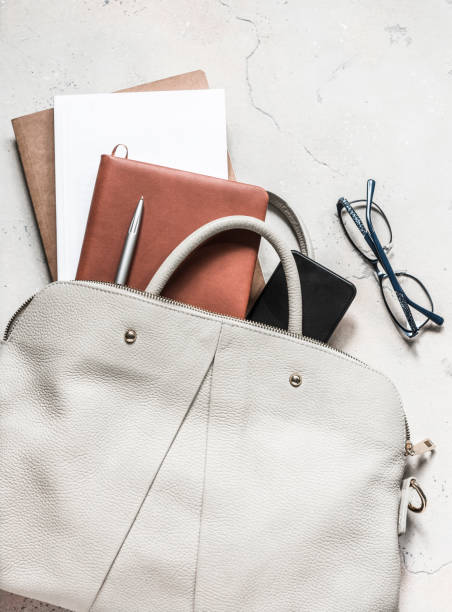 istock Women's bag with office accessories on a light background, top view 1177052043