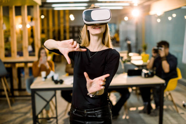 istock Woman in VR headset touching objects in virtual reality. Girl interacting with 3d visualization. Modern IT product test on digital simulator concept. Team of IT workers on the background 1177054237