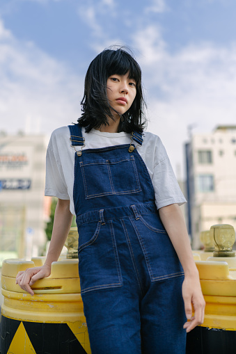 A portrait of a young and confident natural beauty woman with no make-up looking at camera under the clear sky.