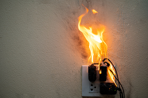 On fire adapter at plug Receptacle on white background, Electric short circuit failure resulting in electricity wire burnt