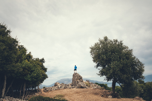 Tourist standing on an old ruin at ancient town Sami, Kefalonia island, Greece.