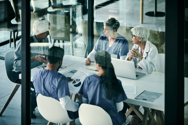 He always leads by example Shot of a group of medical professionals having a meeting together inside a boardroom at a hospital healthcare technology stock pictures, royalty-free photos & images