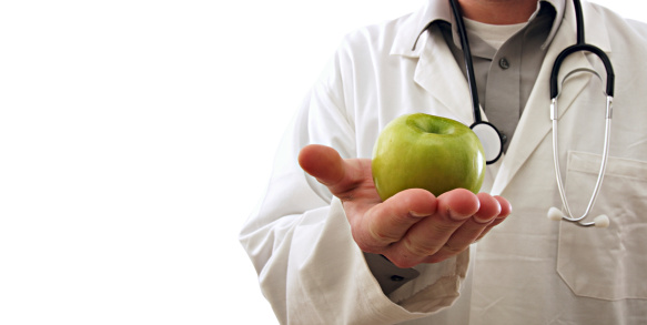 a doctor holding an apple isolated on white.