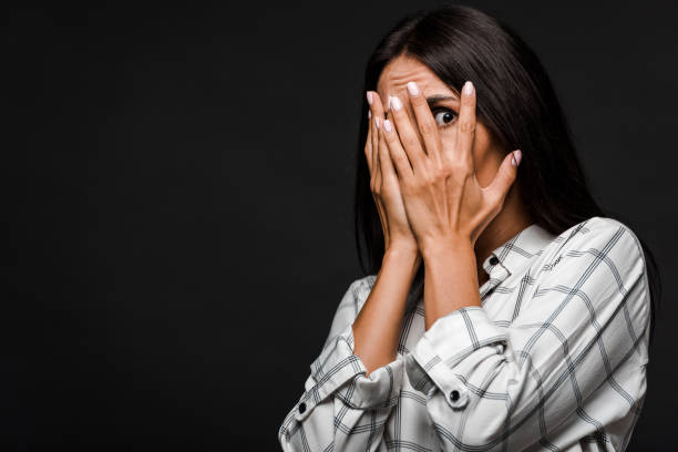 istock scared woman covering face isolated on black 1177077375