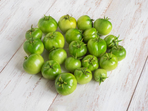 istock Green unripe tomatoes on a white wooden table. 1177080564