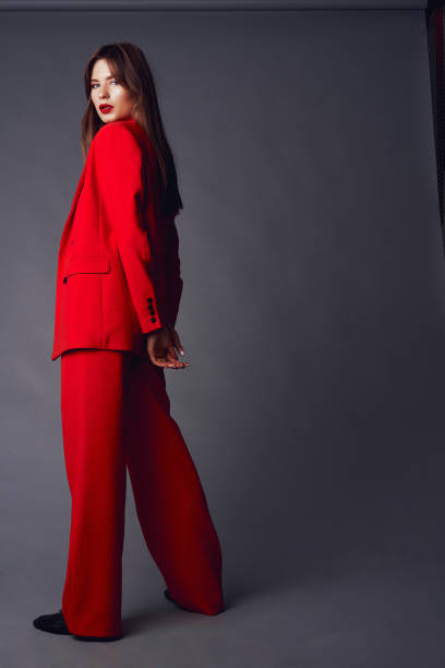 istock Young woman in red suit. Grey background 1177080589