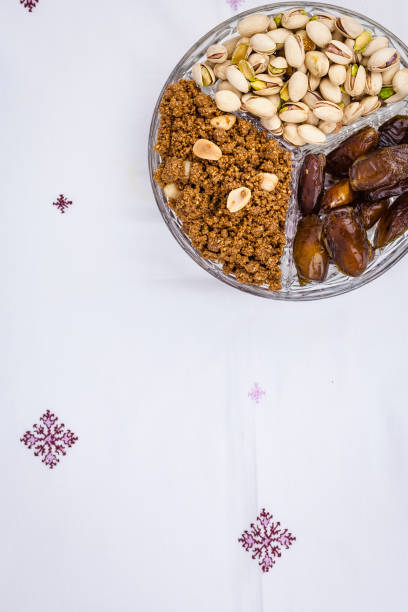 Top view shot of a three split glass plate with typical moroccan muslim iftar sweet tasty and nutritious fast breakers pistachio, dates and almond sfouf. Image vertical with space to include text.