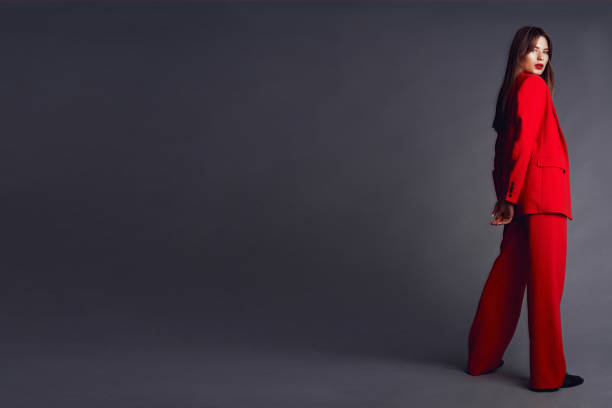 istock Young woman in red suit. Grey background 1177081393