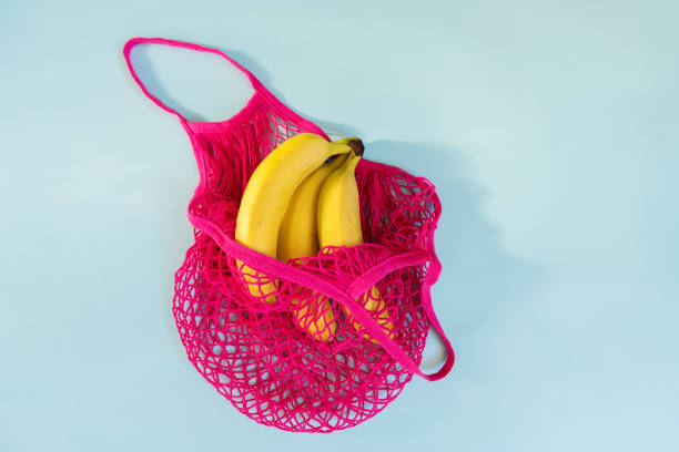istock Three yellow ripe bananas in a fuchsia eco cotton string bag on a pastel blue background 1177081966