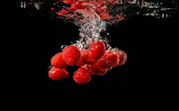 istock Red Raspberries Falls under Water with a Splash, isolated on black background. 1177081972