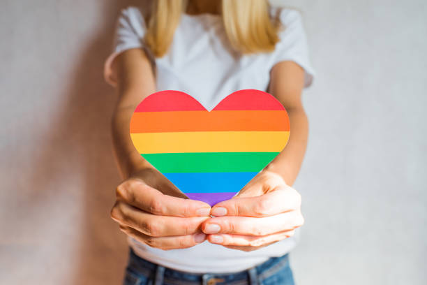 woman holds in hands a heart in the colors of the rainbow. young beautiful girl. lgbt history month. pride month. lesbian gay bisexual transgender. lgbt flag. love, human rights, tolerance. lgbtq+ - homosexual beautiful sensuality love imagens e fotografias de stock