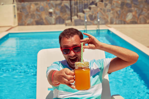 istock Attractive man drinking juice on the swimming pool. Summer concept. 1177086174