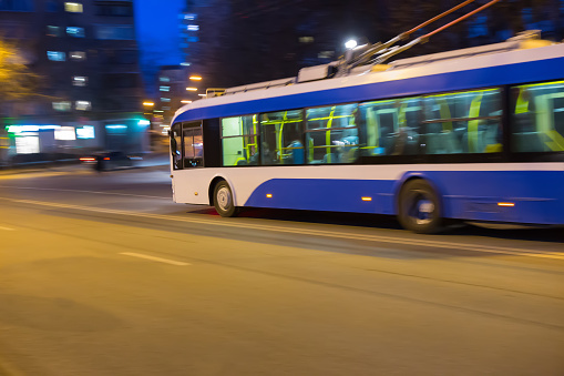 Trolleybus moves at high speed on city street.