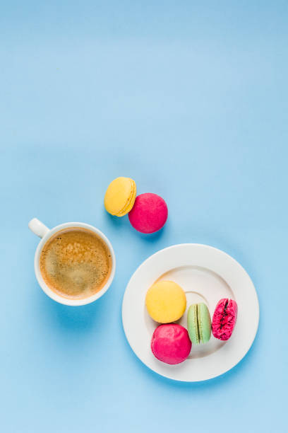 istock Multicolored macaroons with a white Cup of coffee on a blue background, top view, flat lay with copy space 1177088712