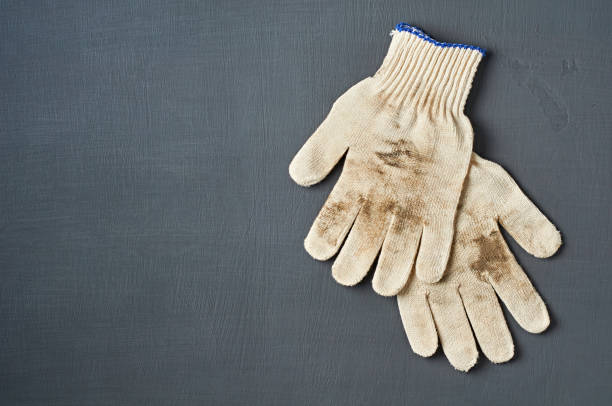 istock Two dirty protective white textile gloves after hard work lies on dark scratched concrete table in workshop. Space for text. Top view 1177090321