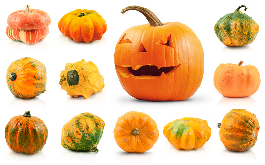 Stock photo showing a pumpkin man on a lawn prepared for Halloween night - All Hallow's Eve. A stack of three orange pumpkins with scary face carved into the top gourd. A pumpkin by the front door indicates that the house is happy to accept Trick or Treaters / children dressed up for a night of Trick or Treat / Treating.