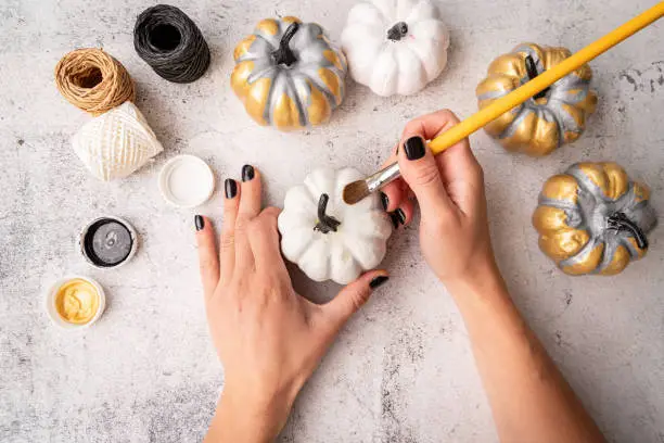 Photo of Female hands with black nails painting pumpkins for halloween