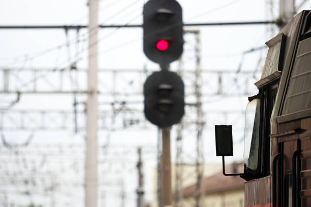 Train stands at the crossing, red light semaphore. Traffic light shows red signal on railway