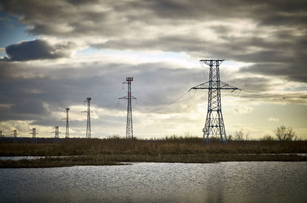 istock High voltage power tower pylon, lake water cloudy sky 1177096649
