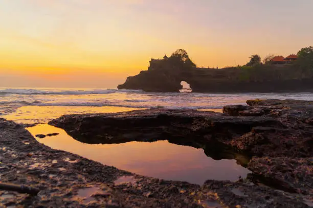 Photo of Rock cliff near Pura Tanah Lot, in Bali at sunset. It is one of the most popular of tourist attraction. Indonesia. Nature landscape background of travel trip and holidays vacation in Indonesia.