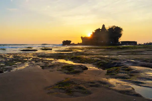 Photo of Pura Tanah Lot, the water temple, in Bali at sunset. It is one of the most popular of tourist attraction. Indonesia. Nature landscape background of travel trip and holidays vacation in Indonesia.