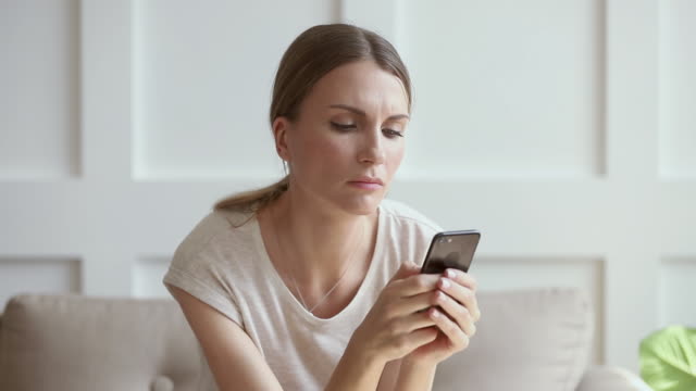 Jealous worried young woman holding phone waiting for mobile call