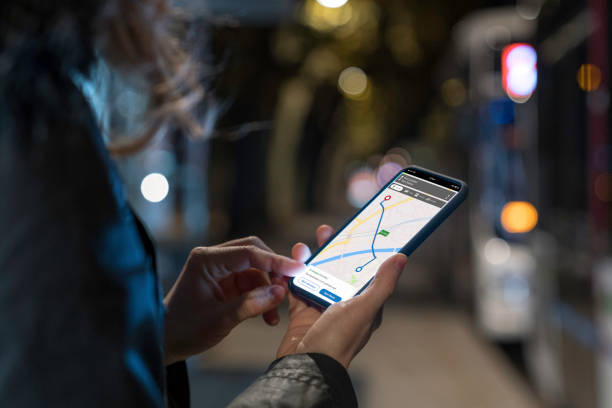 mujer mirando el teléfono iluminado con mapa de navegación fotografiado por la noche en una ciudad - back lit fotografías e imágenes de stock