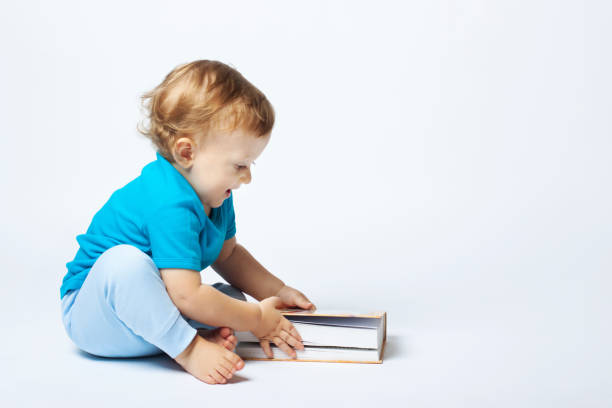 istock Cute baby boy sitting with book on the white background 1177106412