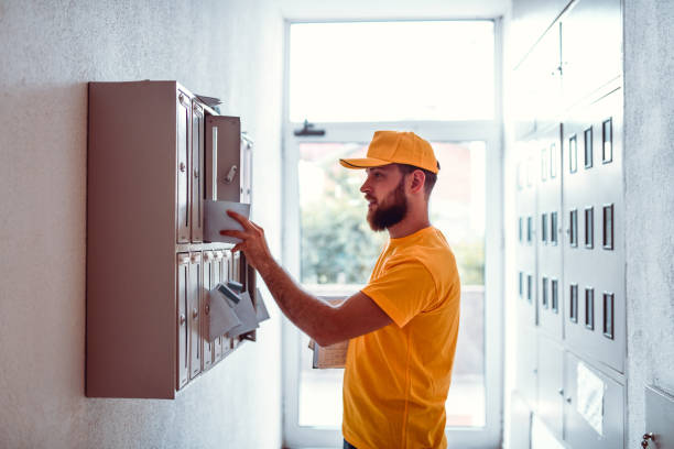 マンションの郵便受けで手形を配達する郵便配達員 - postal worker delivering mail post office ストックフォトと画像