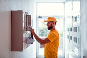 Postman Delivering Bills In Apartment Building Mailbox