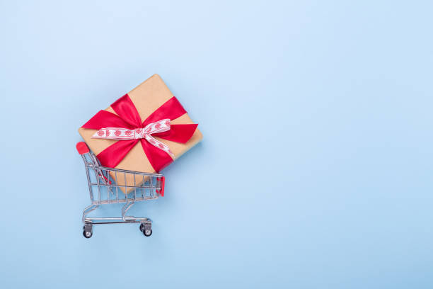 Mini shopping carts and gift box on blue background Concept of Christmas sale Top view Copy space stock photo