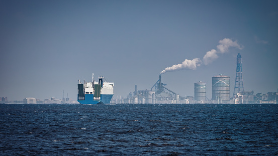 A ship in Tokyo Bay with Japanese factories in the background.