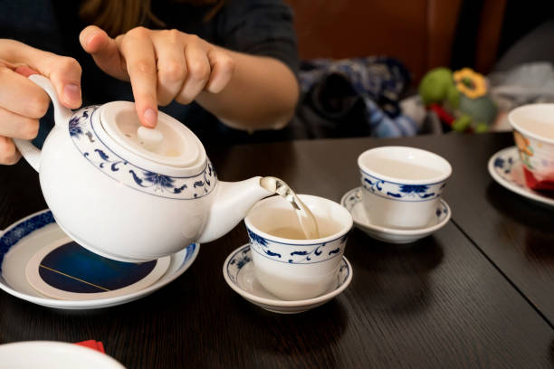 teapot in the hands of a girl pouring green tea into beautiful chinese cups - tea cup cup old fashioned china imagens e fotografias de stock