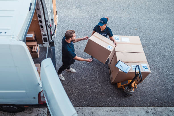 Coworkers rushing to load packages in a delivery van Delivery workers using a Hydraulic Hand Pallet Truck to load a delivery van. distribution warehouse stock pictures, royalty-free photos & images