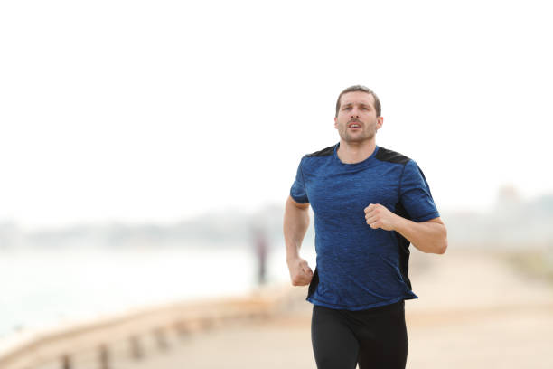 istock Runner is running towards camera training on the beach 1177118467